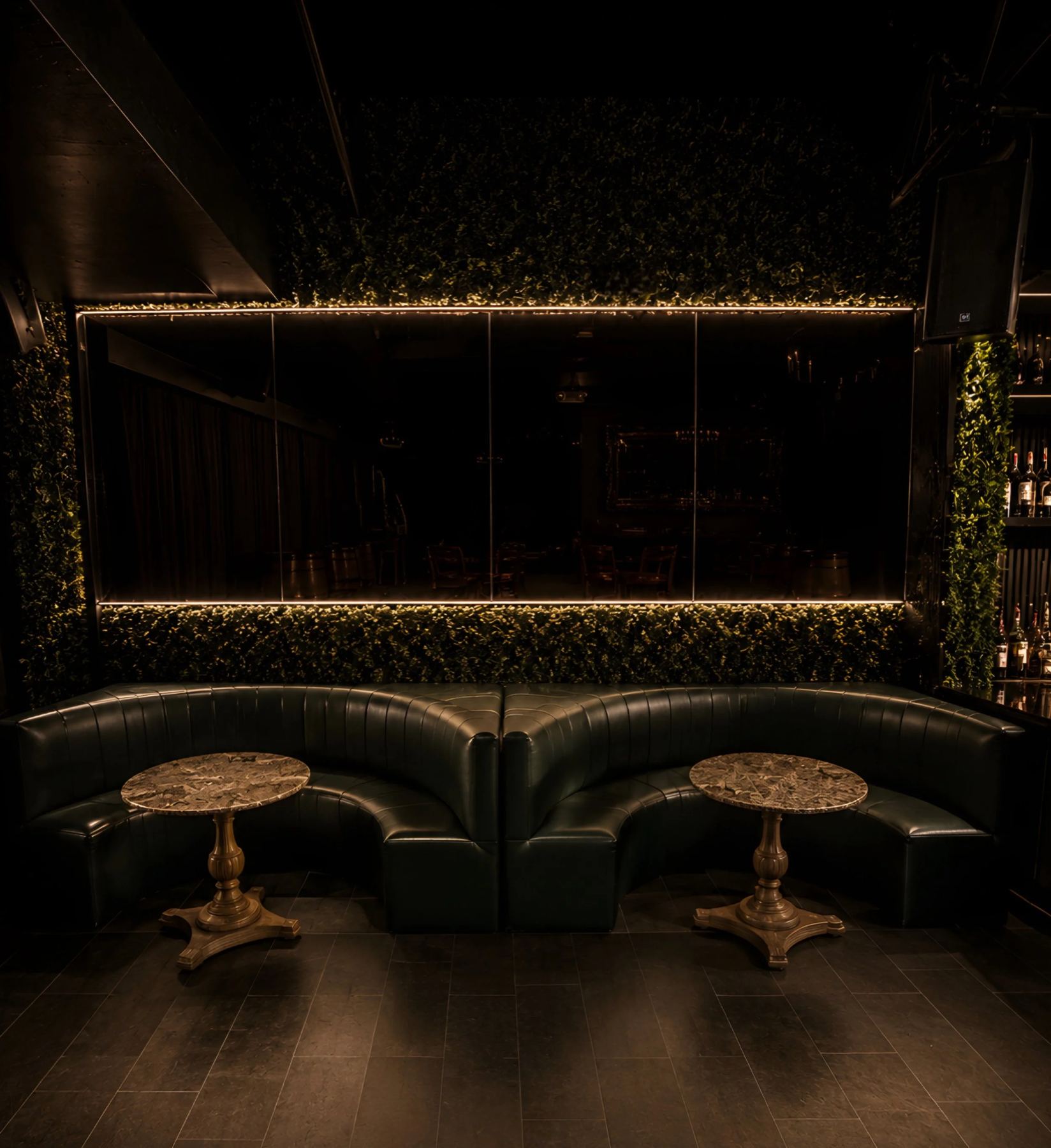 Curved green leather booths beneath the mirror