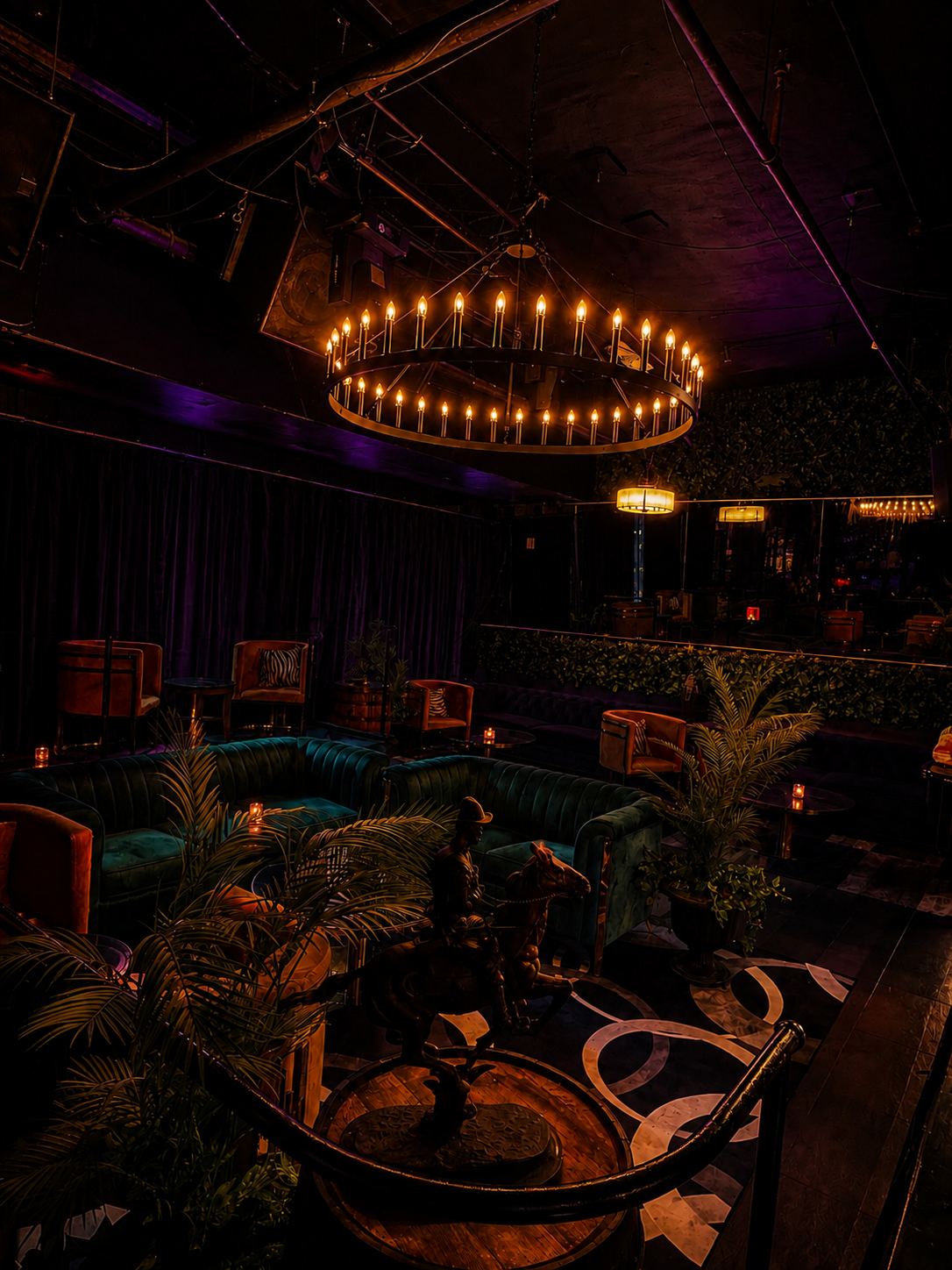Candle-lit green velvet sofas under the chandelier