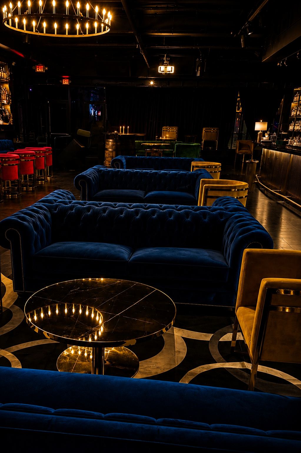 Midnight-blue chesterfield sofas and gold-trimmed chairs under the ring chandelier