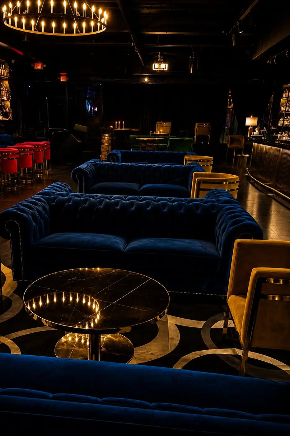 Midnight-blue chesterfield sofas and gold-trimmed chairs under the ring chandelier