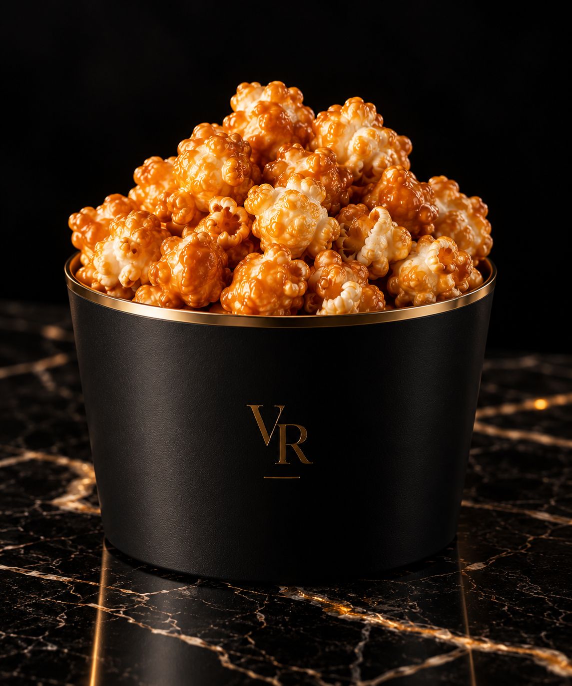 Caramel popcorn in a black and gold Velvet Rail bucket on black marble